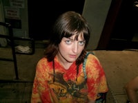 a woman in a tie dye t - shirt standing on a street