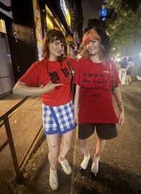 two women posing in front of a building at night